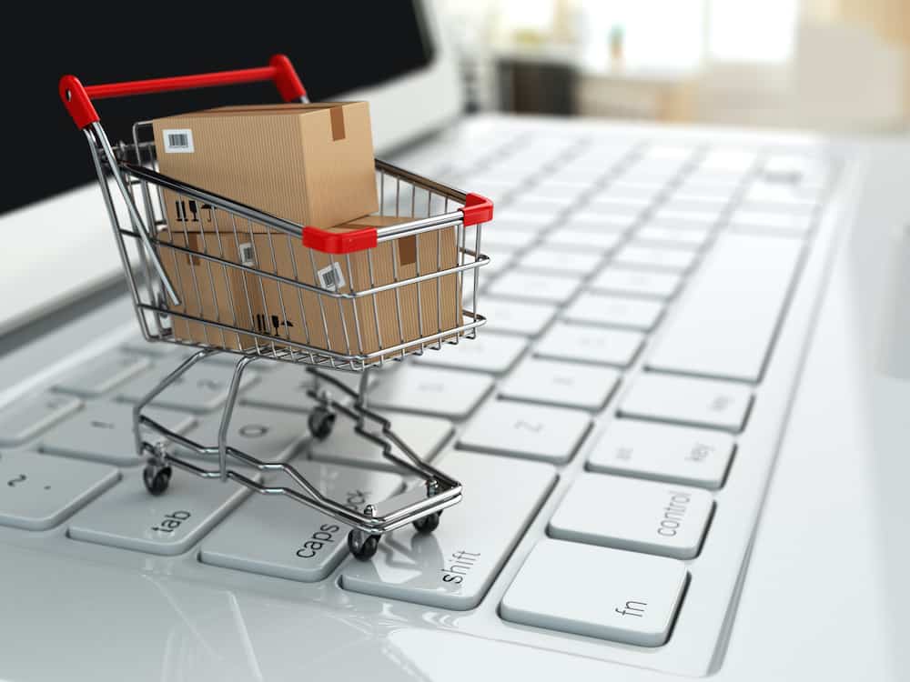 E-commerce. Shopping cart with cardboard boxes on laptop. 3d